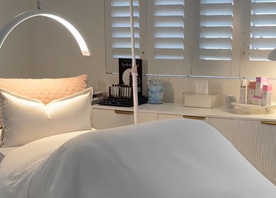 Serene treatment room at The Dermal Collection in Cape Town, Western Cape, ZA with cozy bedding and products.