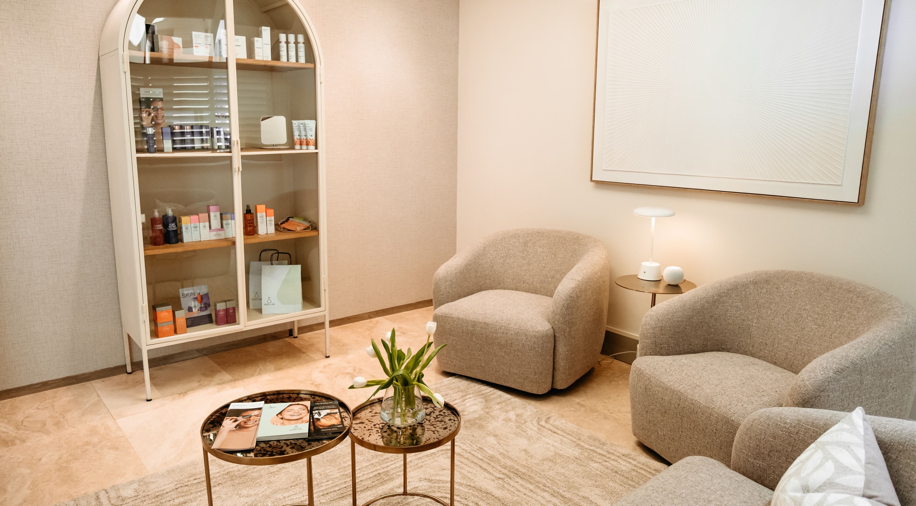 Cozy lounge at The Dermal Collection, Cape Town, Western Cape, ZA with elegant chairs and a display cabinet.