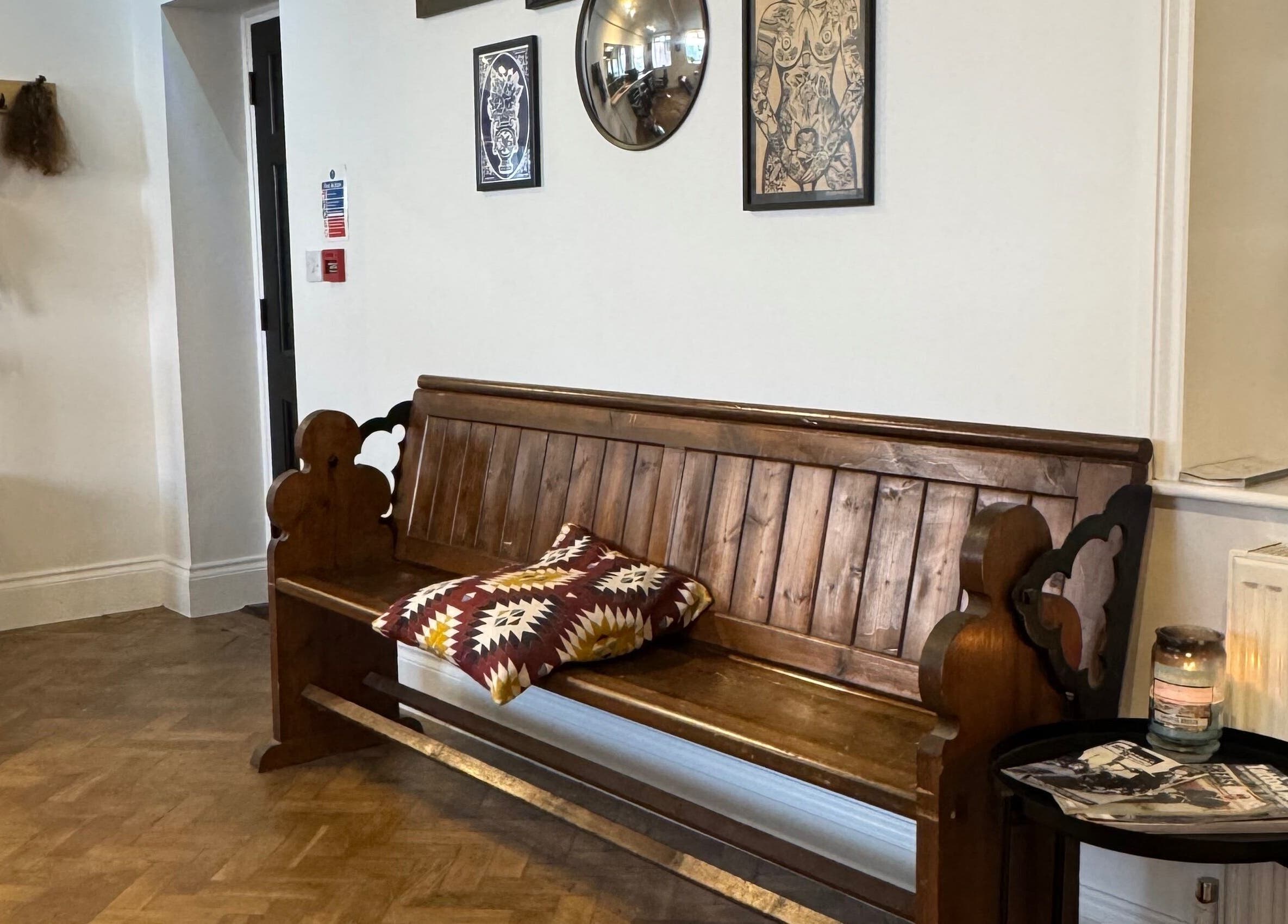 Cozy seating area with wooden bench at Ramblers Barbershop, Hereford, England, GB.