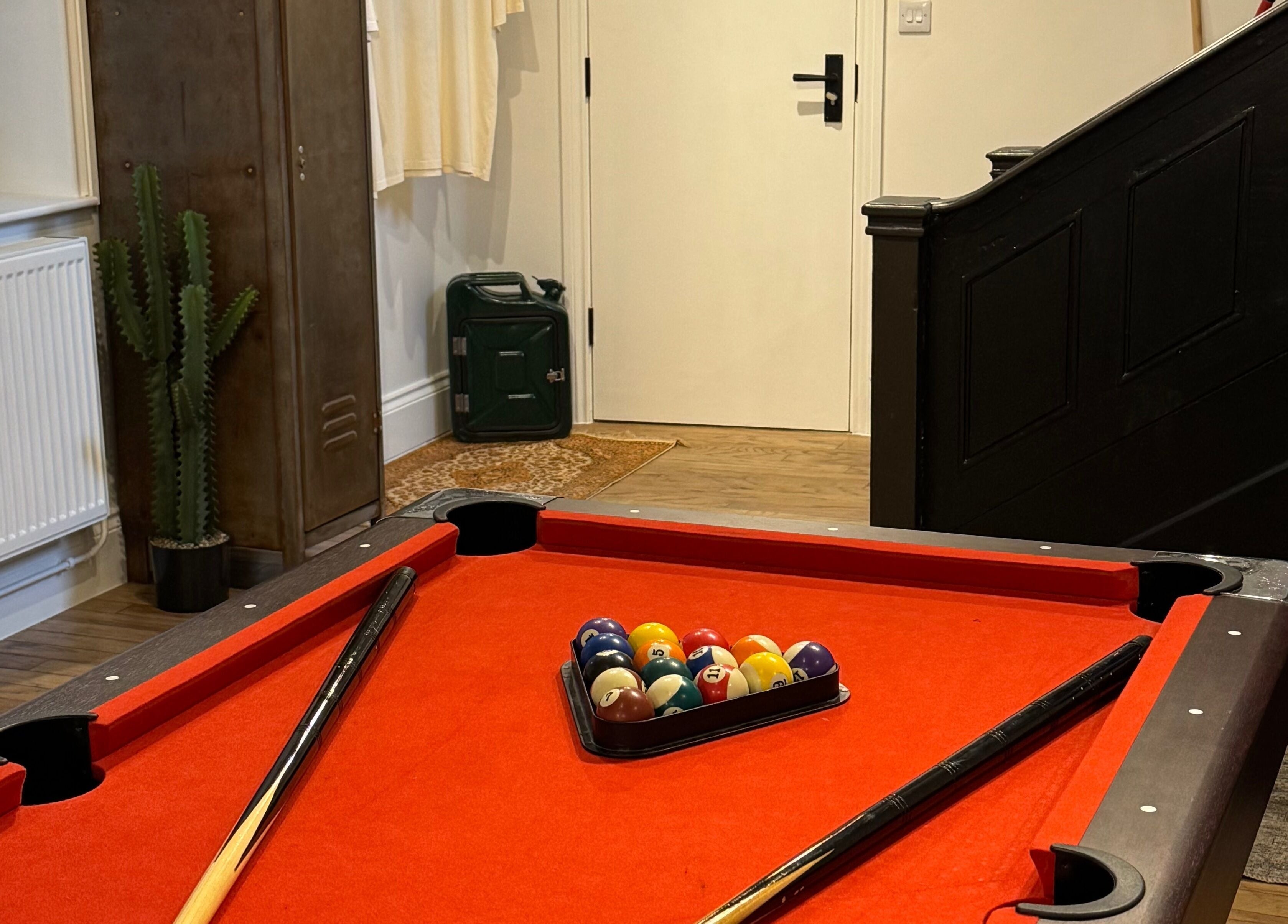 Cozy game area at Ramblers Barbershop, Hereford, England with a red pool table inviting relaxation.