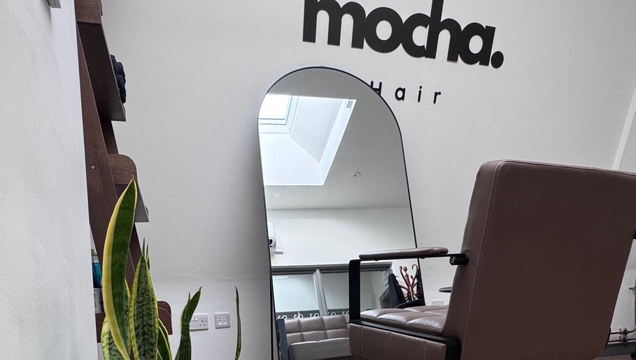 Modern salon interior at Mocha Hair, South Croydon, England. Features stylish seating and a large wall mirror.