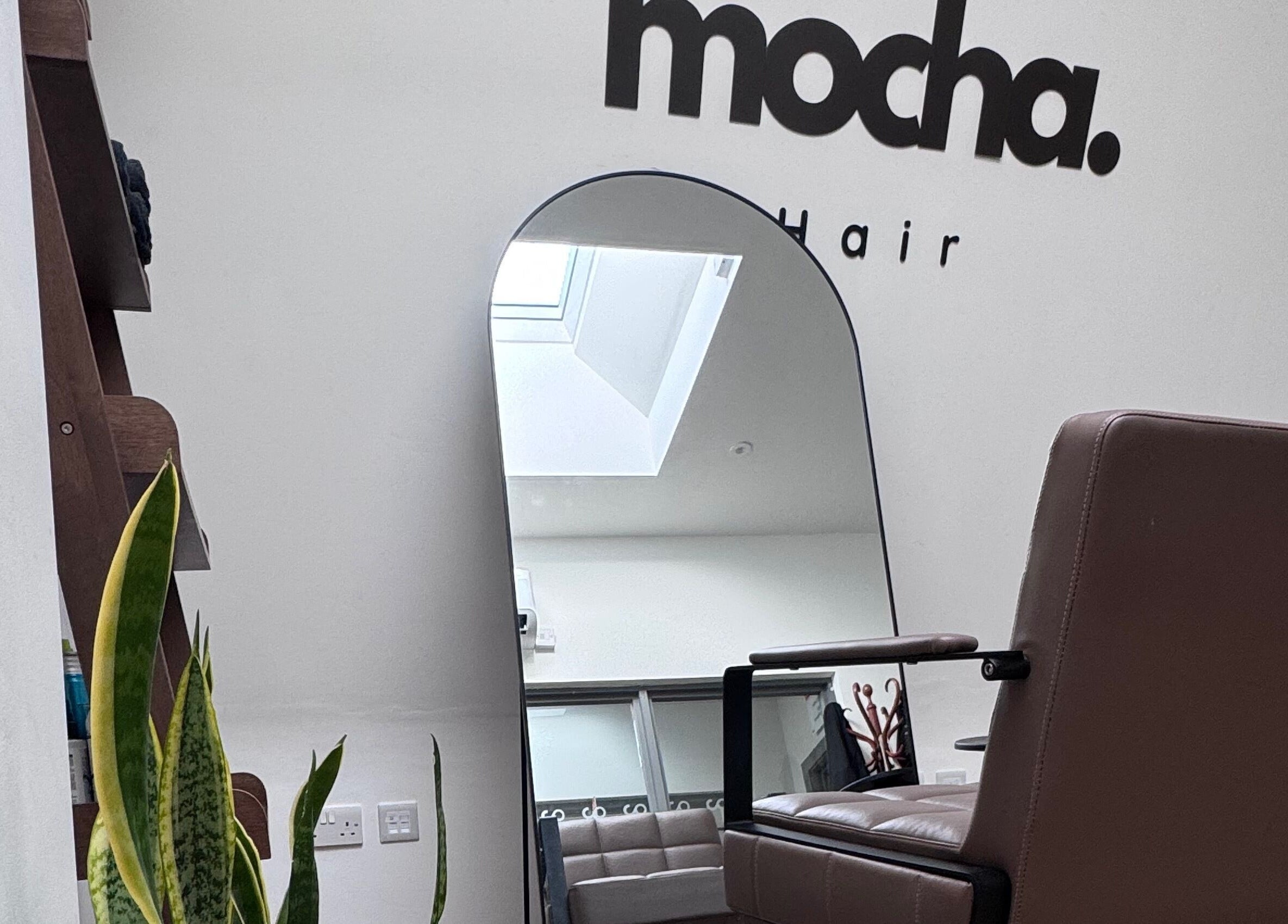 Modern salon interior at Mocha Hair, South Croydon, England. Features stylish seating and a large wall mirror.