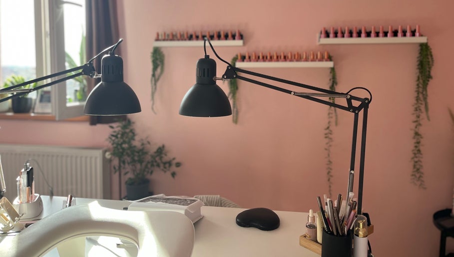 Elegantan interijer salona 'Šmi nails' u Gornjoj Lomnici s visećim lampama i urednim radnim stolom.
