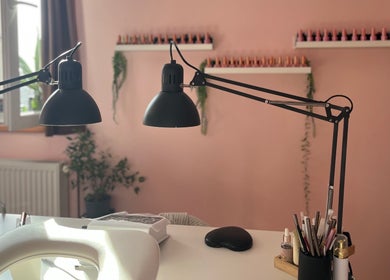 Elegantan interijer salona 'Šmi nails' u Gornjoj Lomnici s visećim lampama i urednim radnim stolom.
