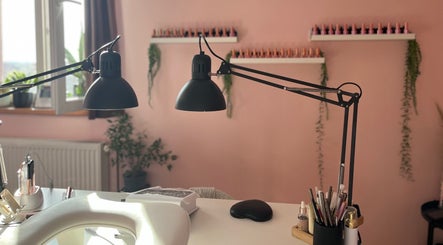 Elegantan interijer salona 'Šmi nails' u Gornjoj Lomnici s visećim lampama i urednim radnim stolom.
