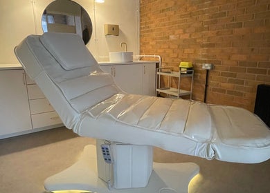 Luxurious treatment bed in serene NL Aesthetics, Worcester, England, GB, showcasing modern amenities.