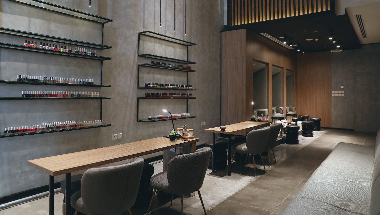 Modern nail salon interior at Beauty Box Nail Spa & Salon, Dhahran, SA, showcasing elegant seating and polish display.