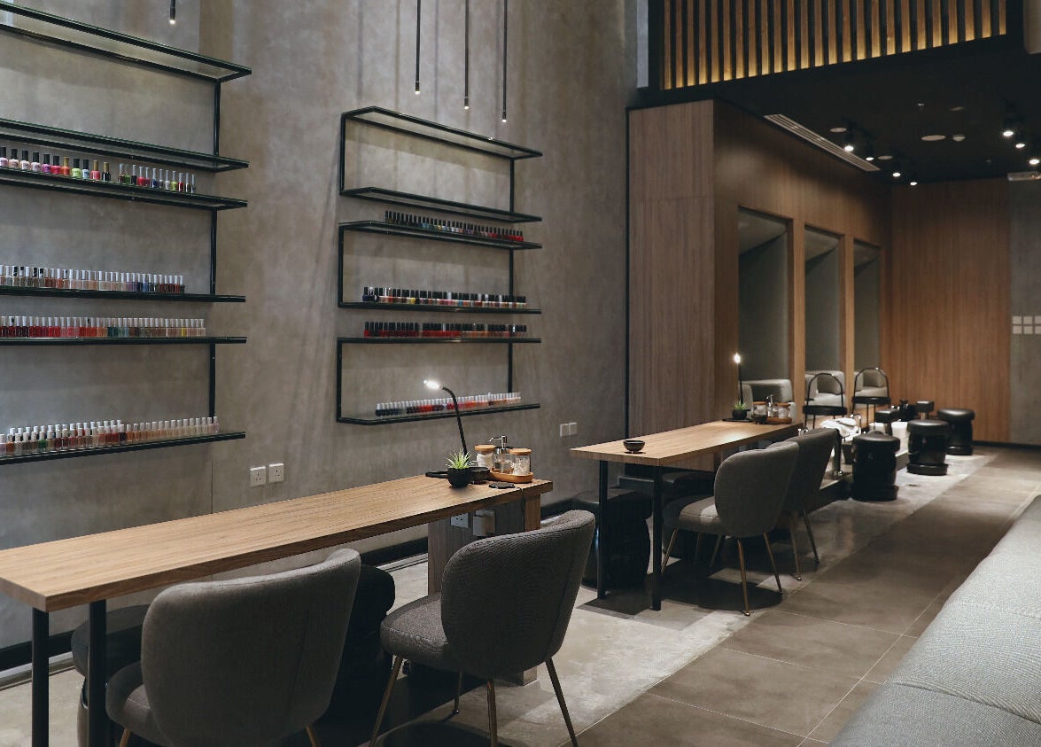 Modern nail salon interior at Beauty Box Nail Spa & Salon, Dhahran, SA, showcasing elegant seating and polish display.