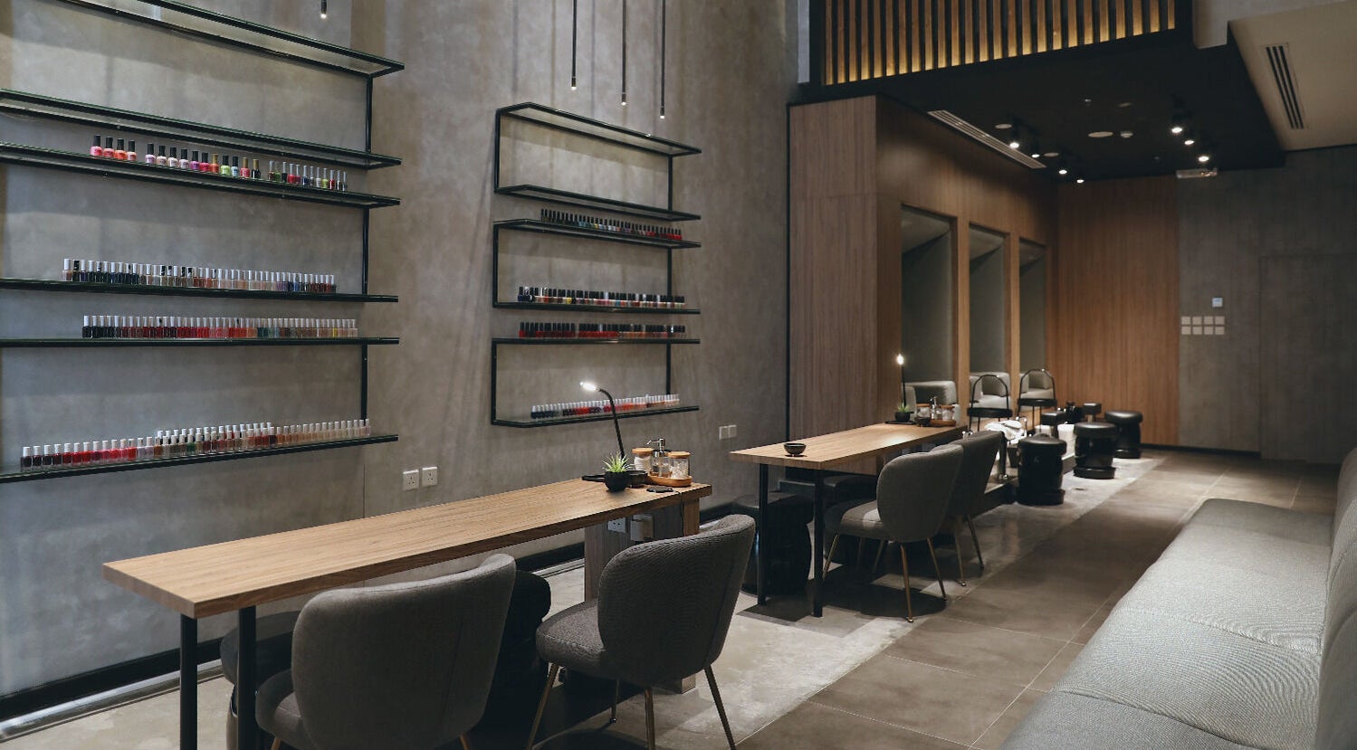 Modern nail salon interior at Beauty Box Nail Spa & Salon, Dhahran, SA, showcasing elegant seating and polish display.