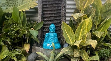 A tranquil Buddha statue amidst lush greenery at Koru Body Soul Māori Healers, Te Awamutu, Waikato, NZ.