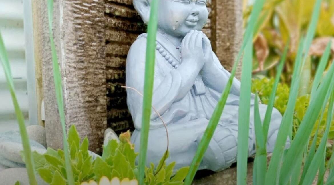 Serene statue amidst foliage at Koru Body Soul Māori Healers, Te Awamutu, Waikato, NZ.