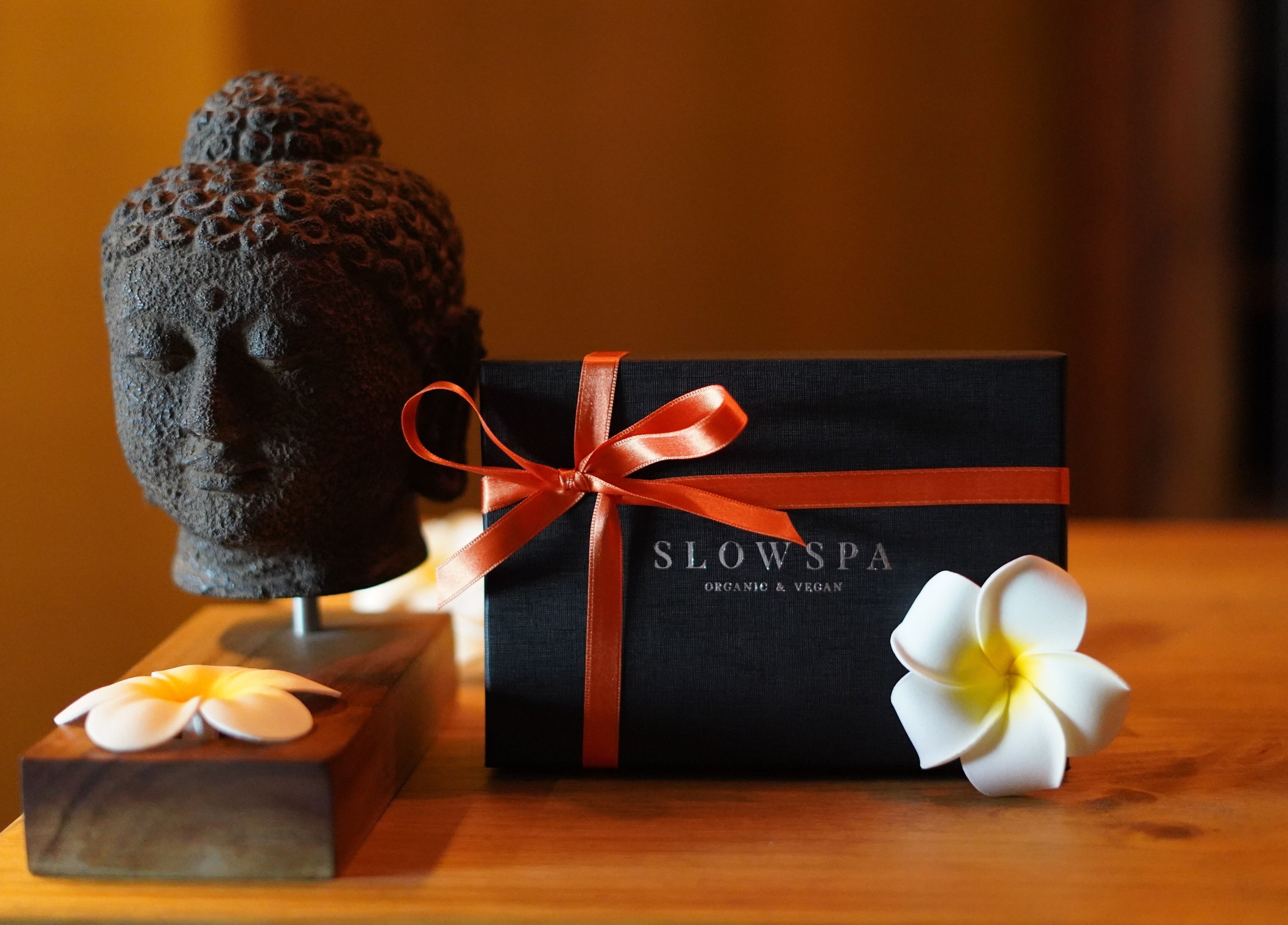 Buda y caja regalo en Slow Bali Spa Barcelona, Catalunya, ES. Ambiente sereno con flor blanca decorativa.