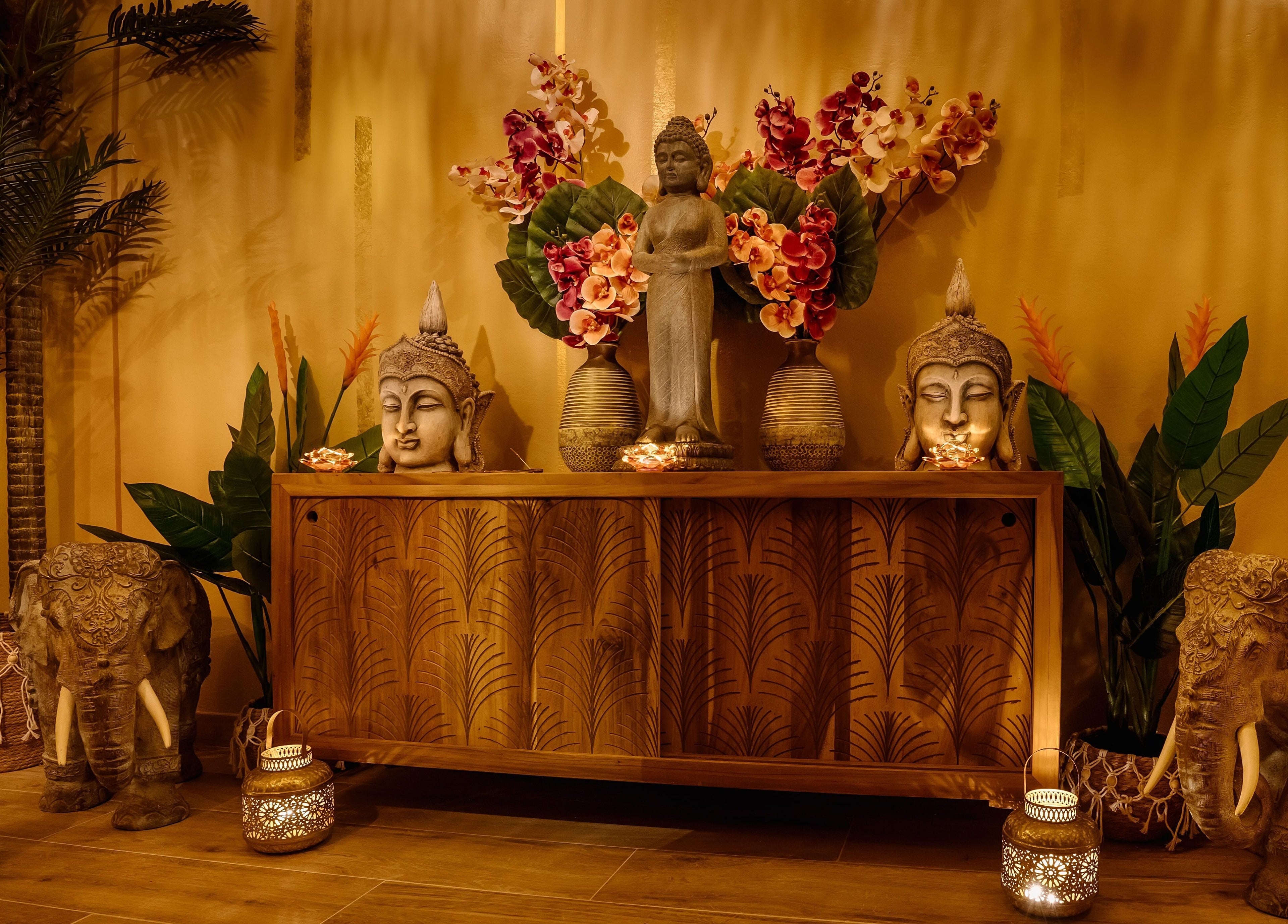 Escultura budista en Pura Bali Massage Spa, Barcelona, Catalunya, ES, con decoración zen y flores tropicales.