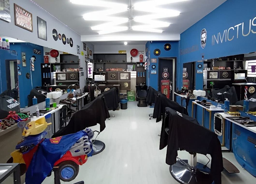 Interior da Barbearia Invictus em Rio Grande Do Sul, BR, mostrando cadeiras e decoração moderna.