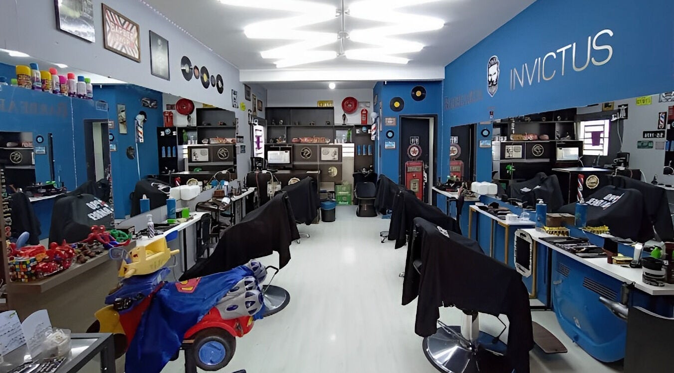 Interior da Barbearia Invictus em Rio Grande Do Sul, BR, mostrando cadeiras e decoração moderna.