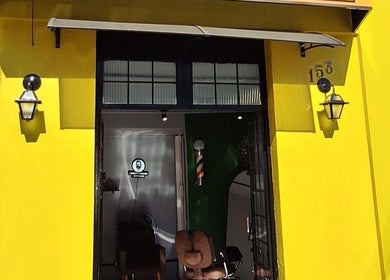 Fachada amarela da BARBEARIA INVICTUS CENTRAL em Rio Grande Do Sul, BR, destacando-se com cadeiras de barbearia.