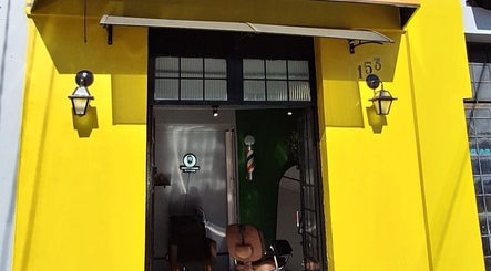 Fachada amarela da BARBEARIA INVICTUS CENTRAL em Rio Grande Do Sul, BR, destacando-se com cadeiras de barbearia.