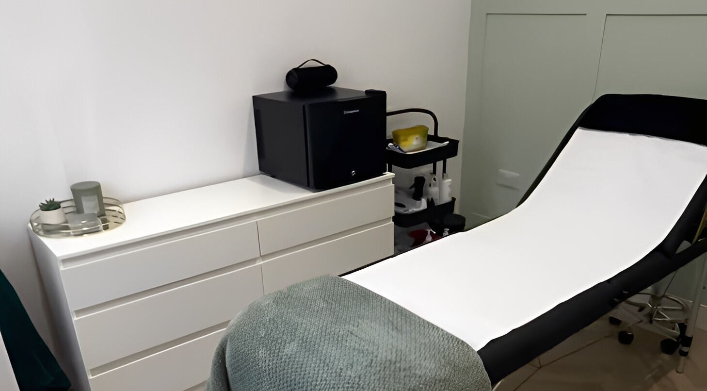 Modern treatment room at Flawless, Lostock Hall, England, GB, featuring a sleek bed and storage unit.