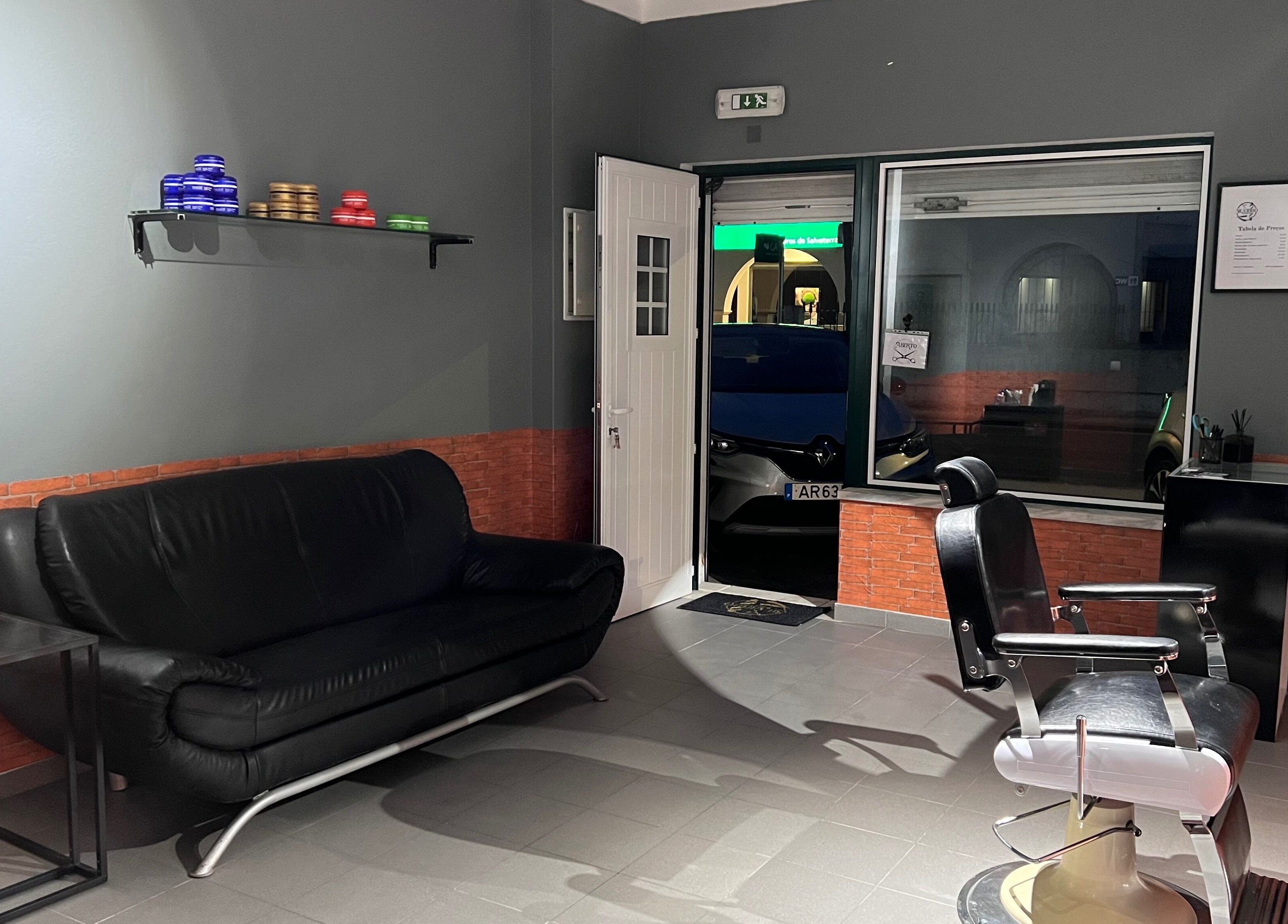 Interior da Silvinho Barbearia em Foros de Salvaterra, Santarém, PT com sofá e cadeira de barbeiro.