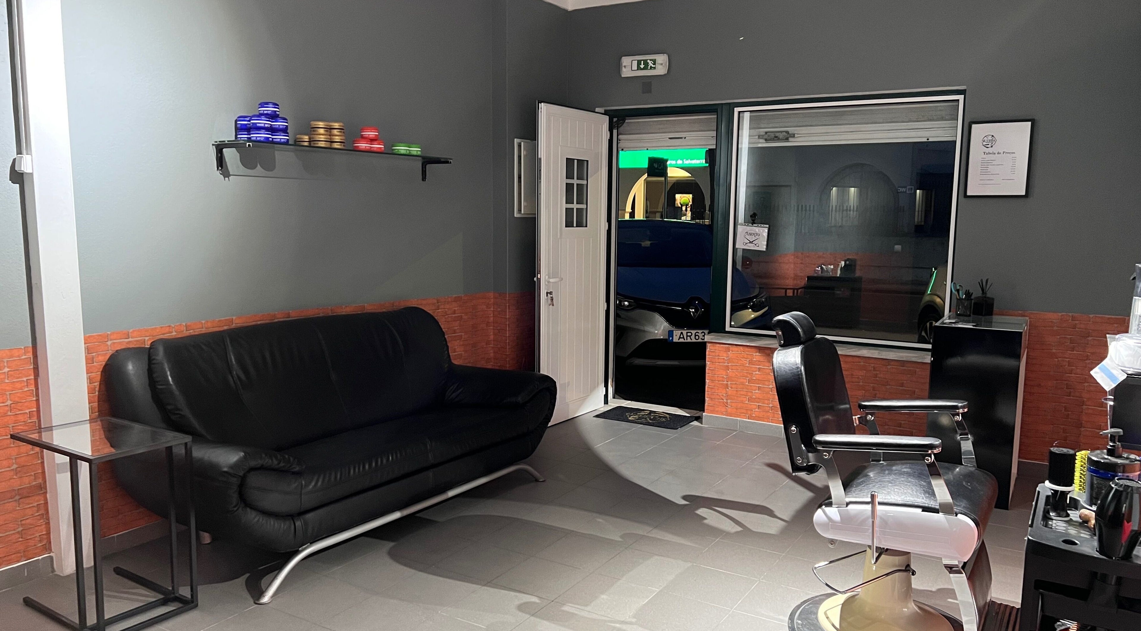 Interior da Silvinho Barbearia em Foros de Salvaterra, Santarém, PT com sofá e cadeira de barbeiro.