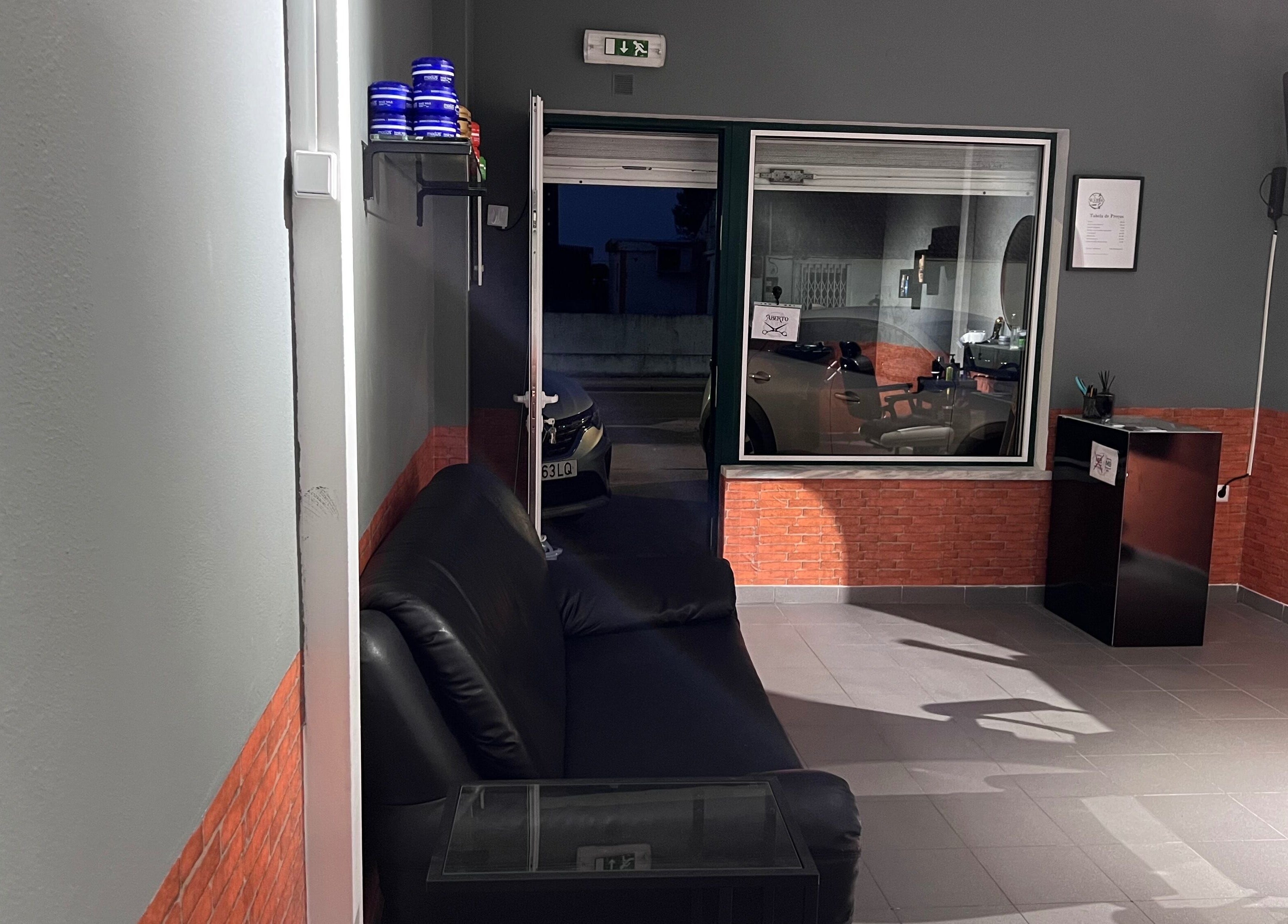 Interior acolhedor da Silvinho Barbearia em Foros de Salvaterra, Santarém, PT, com sofá e cadeira de barbearia.