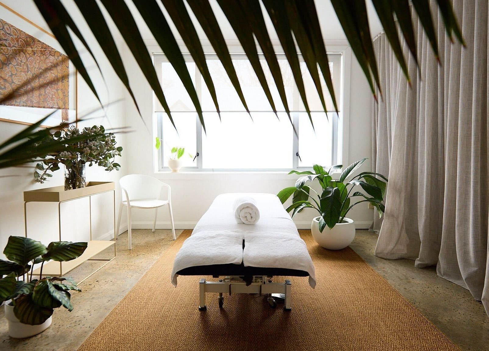 Spa room at The Deep Unwind, Woollahra, New South Wales, AU, featuring a massage bed amid lush plants.