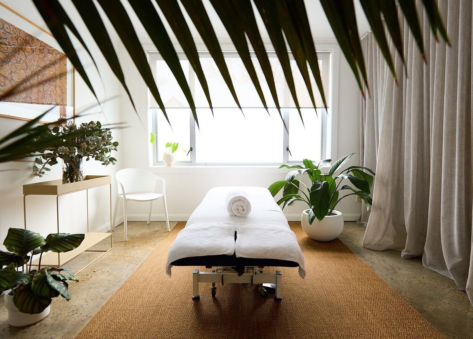 Spa room at The Deep Unwind, Woollahra, New South Wales, AU, featuring a massage bed amid lush plants.