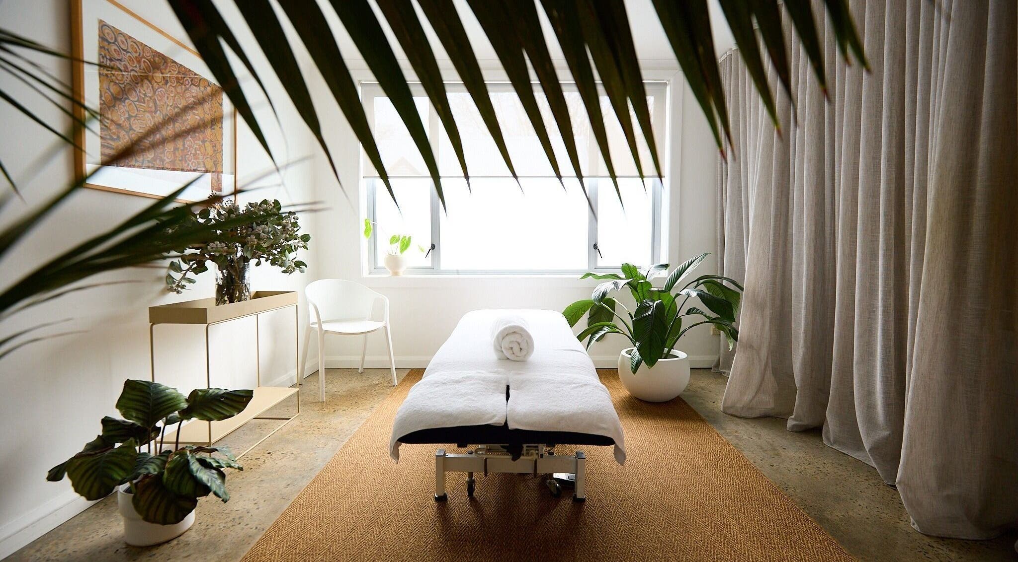 Spa room at The Deep Unwind, Woollahra, New South Wales, AU, featuring a massage bed amid lush plants.