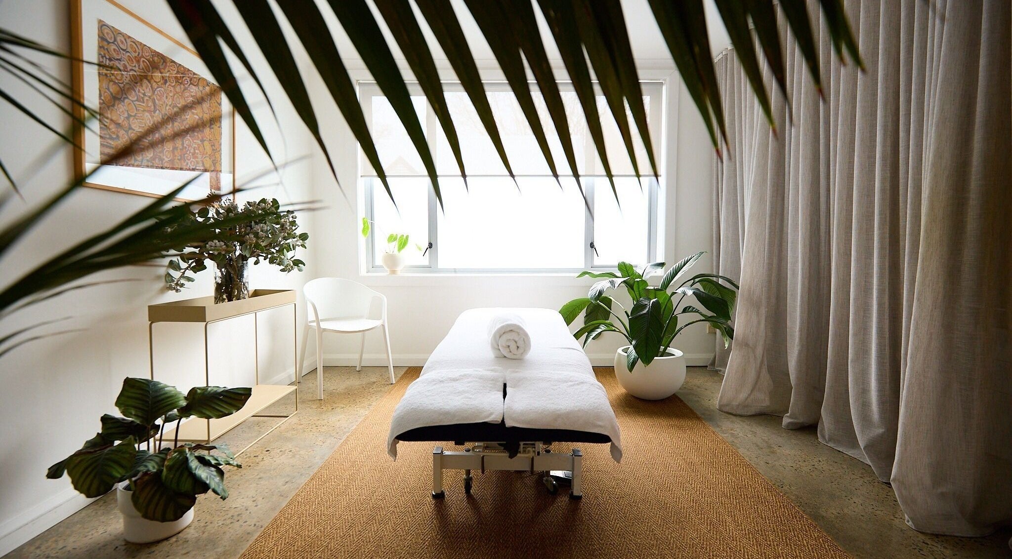 Spa room at The Deep Unwind, Woollahra, New South Wales, AU, featuring a massage bed amid lush plants.