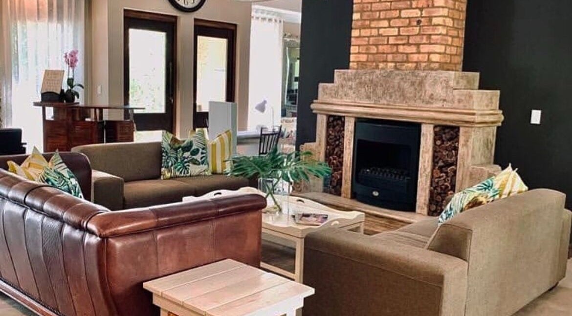 Cozy lounge area at Evident Beauty Salon, Shere, Gauteng, ZA, featuring plush seating and a warm brick fireplace.