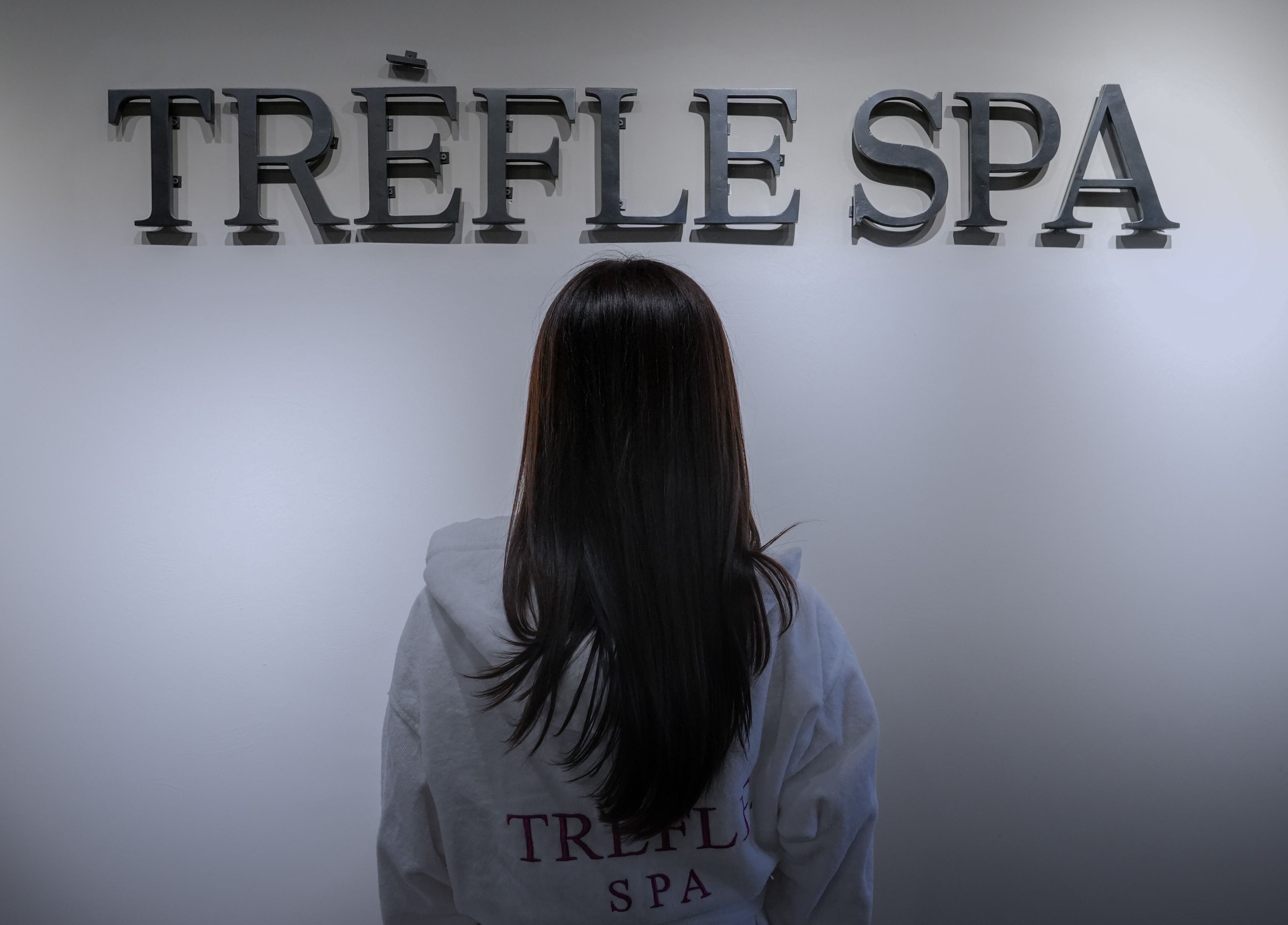 Visitor admiring Trèfle Spa's elegant signage in Al Ain, Abu Dhabi, AE.