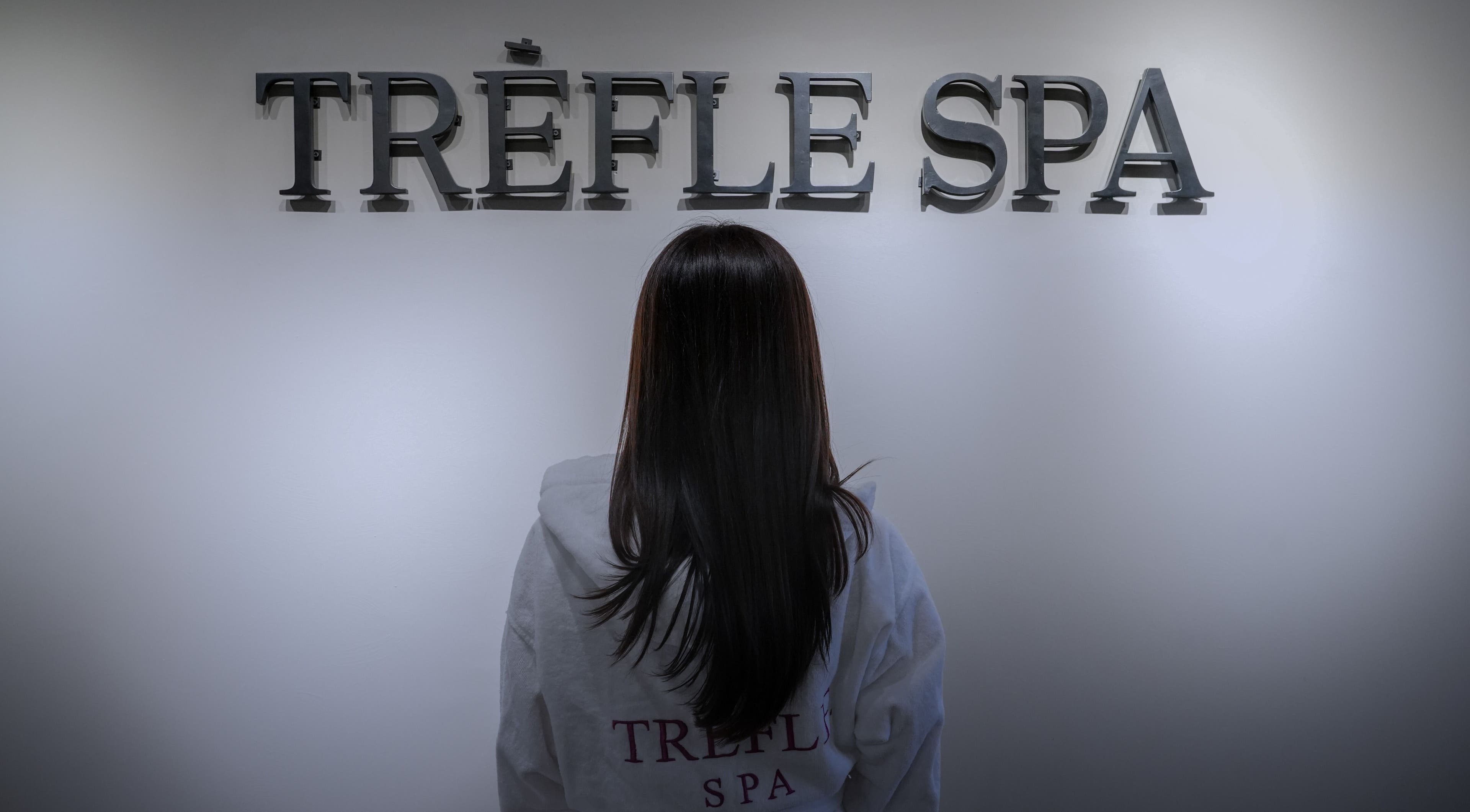 Visitor admiring Trèfle Spa's elegant signage in Al Ain, Abu Dhabi, AE.
