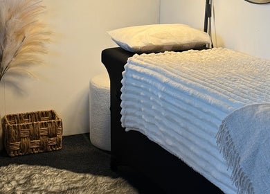 Serene treatment room at By Naums, Tauranga, Bay Of Plenty Region, NZ with plush bed and pampas grass decor.