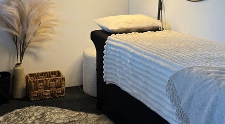 Serene treatment room at By Naums, Tauranga, Bay Of Plenty Region, NZ with plush bed and pampas grass decor.