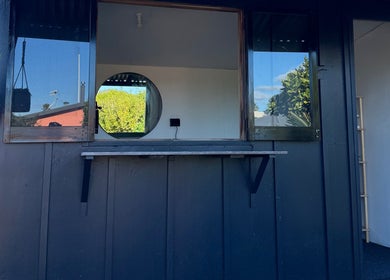 Charming wooden facade at By Naums, Tauranga, Bay Of Plenty Region, NZ with hanging plants and window view.
