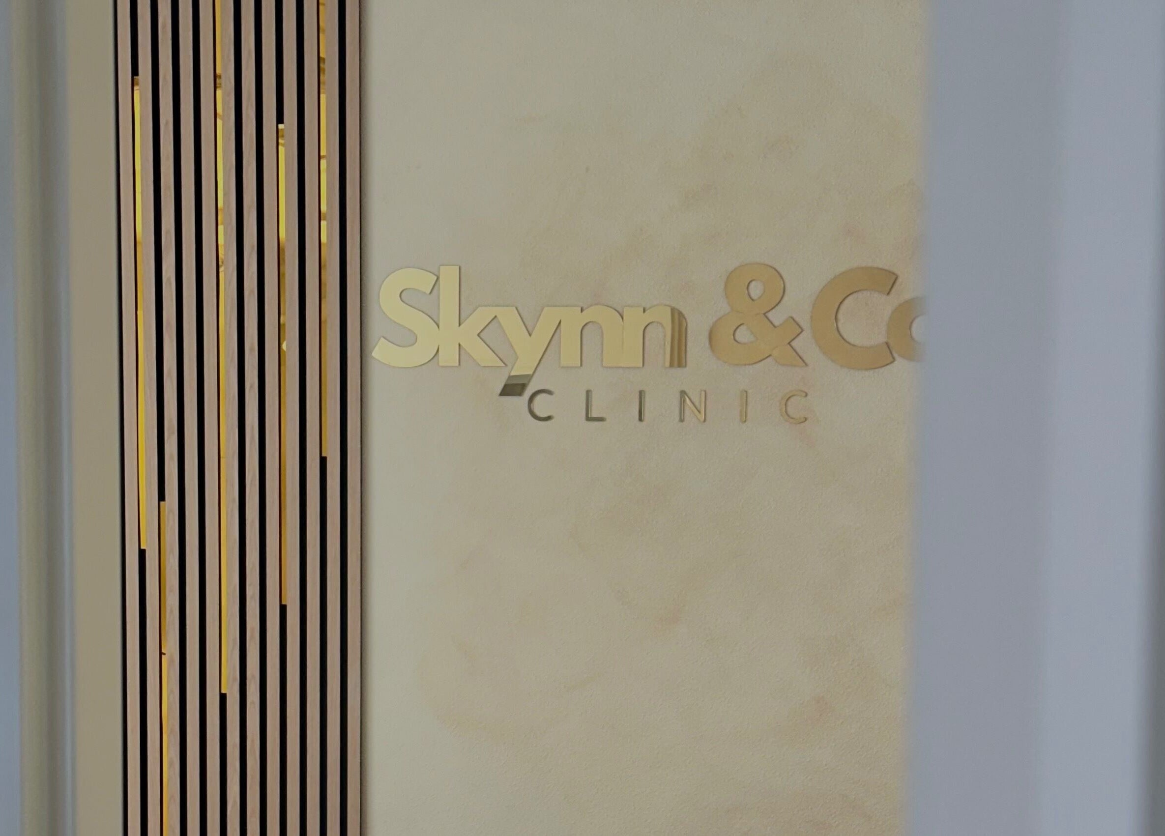 Elegant gold-lettered Skynn & Co. Clinic signage at Apeldoorn, Gelderland, NL interior wall.
