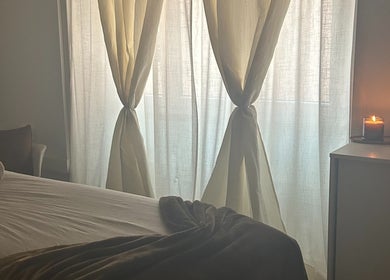 Calming treatment room at Terapeuta Vânia Custódio, Lisboa, Lisboa, PT with soft drapes and lit candle.