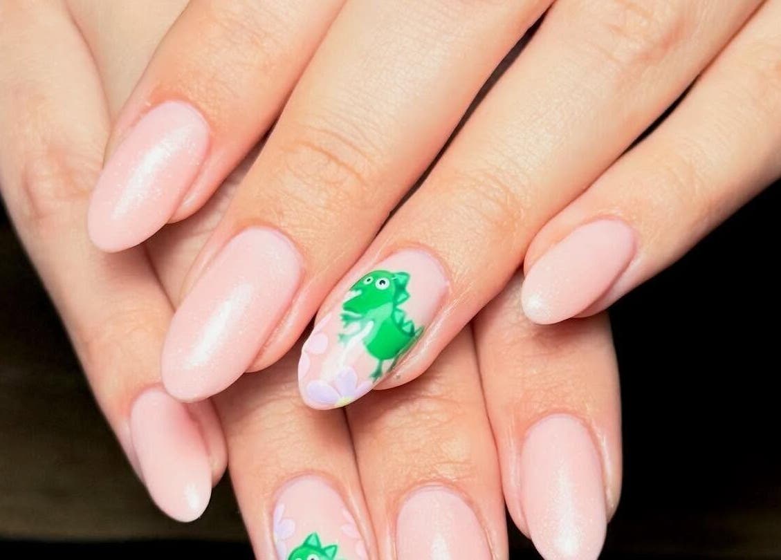 Stylish pink nails with dinosaur art at Toni Michelle Nail Artist, Cleethorpes, England, GB.