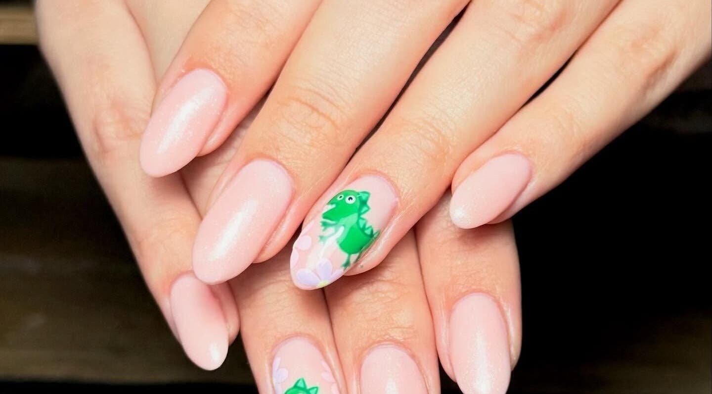 Stylish pink nails with dinosaur art at Toni Michelle Nail Artist, Cleethorpes, England, GB.