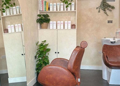 Stylish salon interior of Hue Hair and Beauty in Bristol, England, GB with leather chair and lush plants.