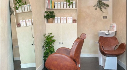 Stylish salon interior of Hue Hair and Beauty in Bristol, England, GB with leather chair and lush plants.