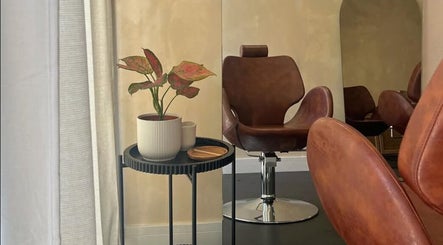Luxurious salon chair at Hue Beauty, Bristol, England, GB, next to a stylish plant decor.
