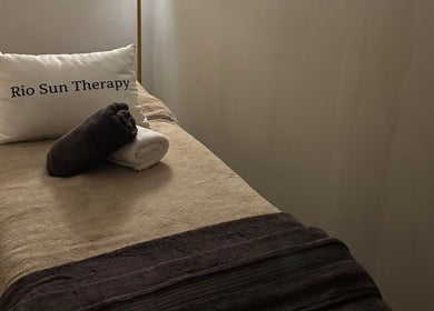 Massage table at Rio Sun Massage Therapy in London, England, GB, prepared with towels and a branded pillow.