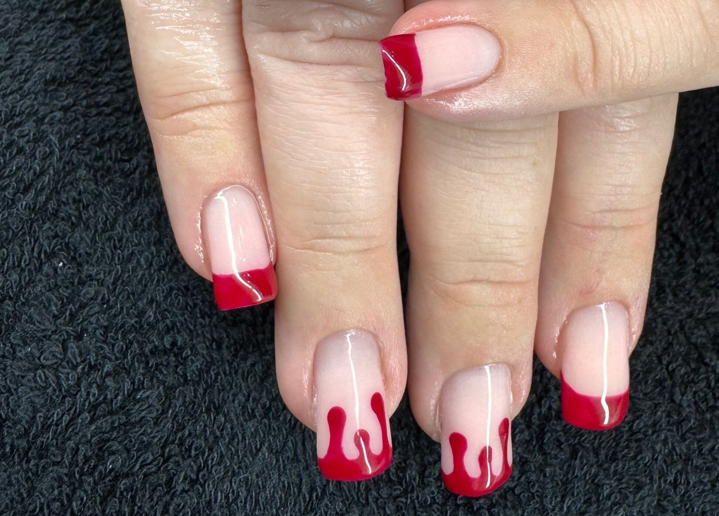 Stylish red-tipped manicure at The Rose Collection, Weston-super-Mare, England, GB on textured black towel.