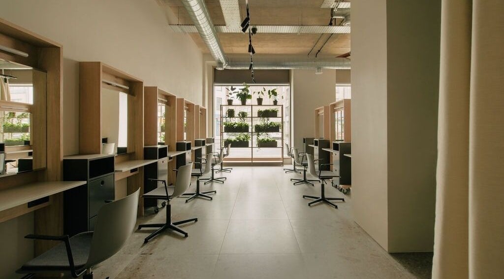 Modern interior of Glasshouse Salon in London, England, GB with stylish chairs and greenery.