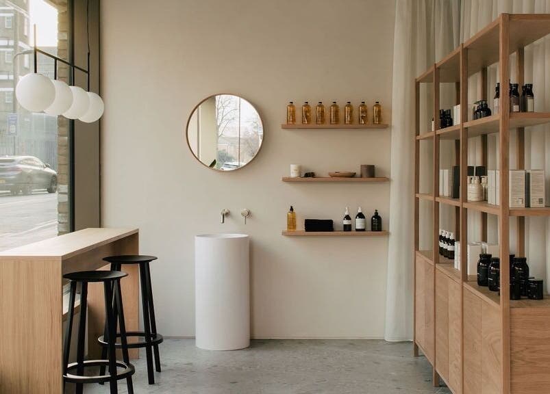 Chic interior of Glasshouse Salon in London, England, GB. Features modern shelving and seating with natural wood tones.