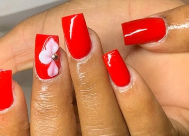 Red nails with pink floral design at Banusti Beauty Nails in Burlington, Massachusetts, US.