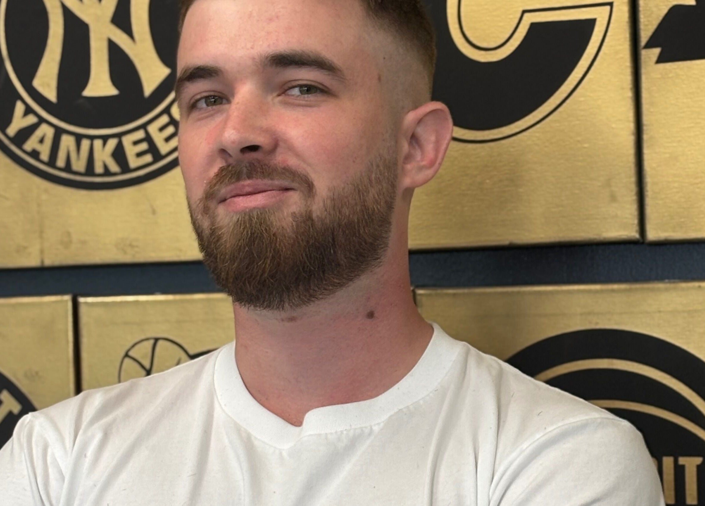 Man with a fresh haircut at Mankind Barbershop, Calgary, Alberta, CA, standing against a stylish wall.