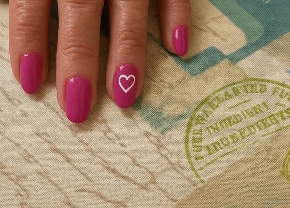 Bright pink nails with white heart design at Mobile Glam, Caerphilly, Wales, GB.