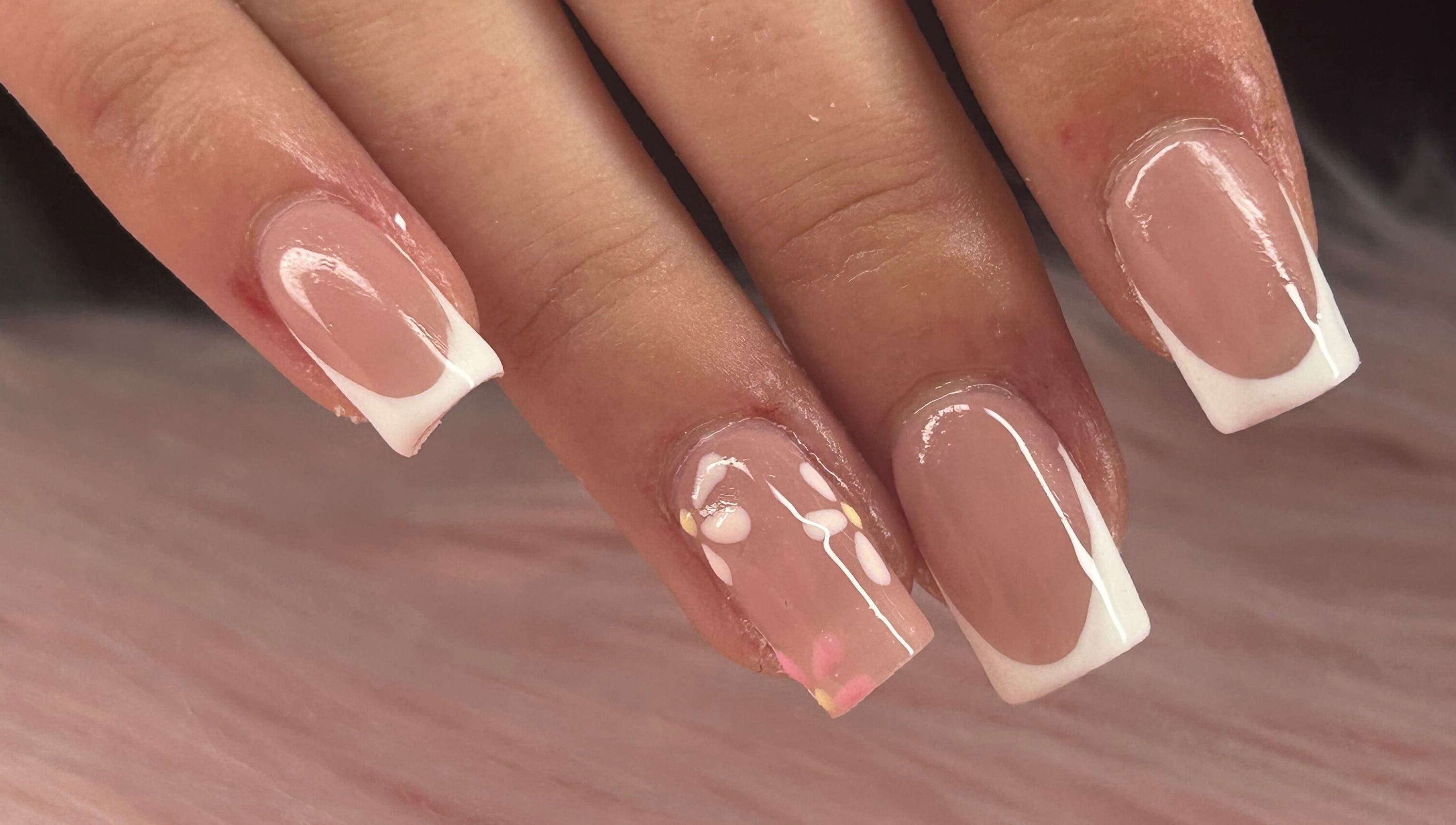 Close-up of French tip nails with delicate floral design at arushisnails, Crawley, England, GB.